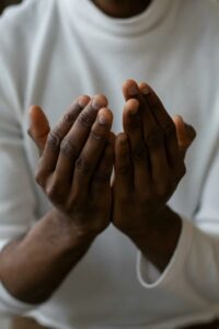 A Black person holding their hands cupped like a prayer or offering.